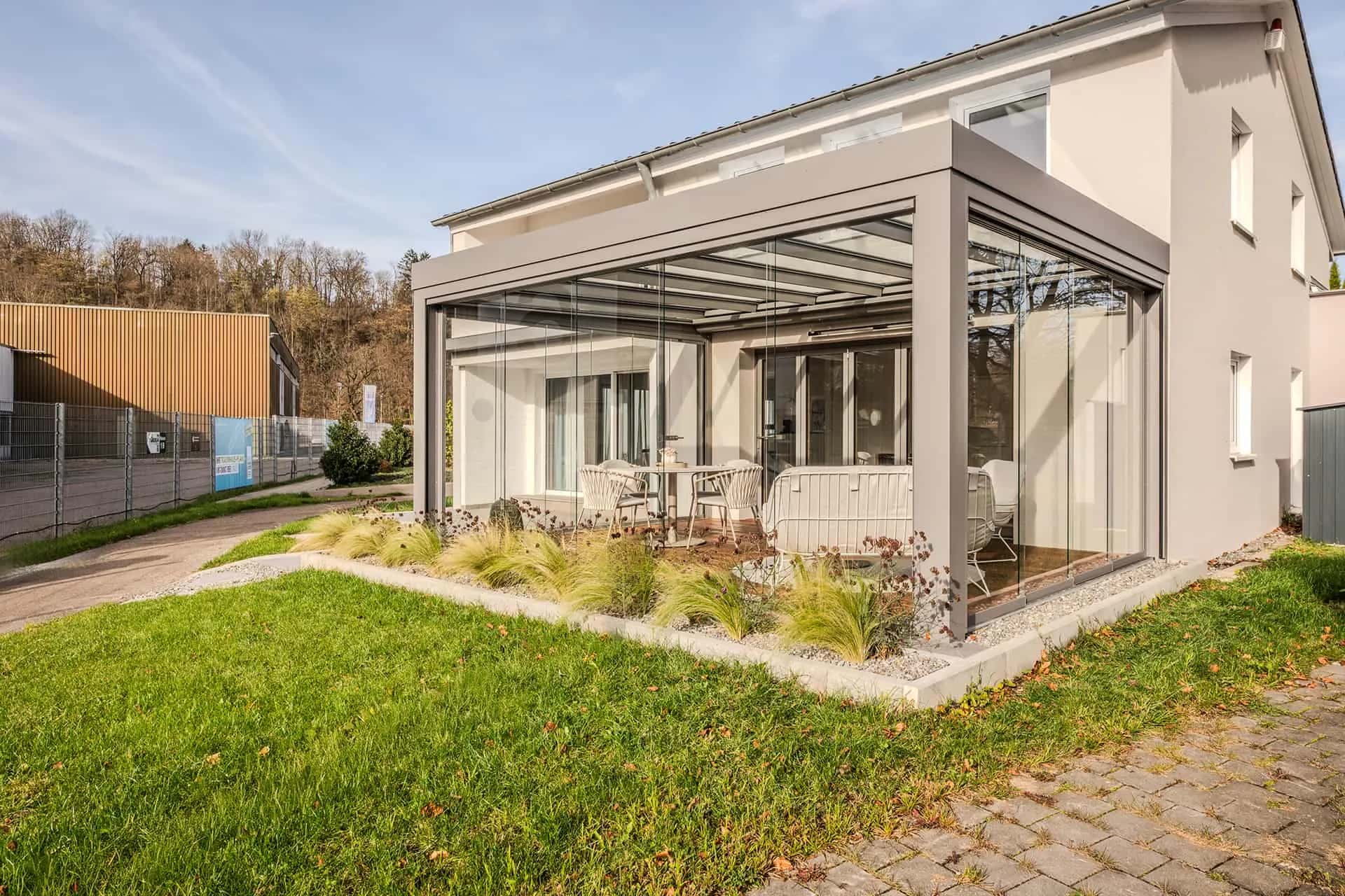Wintergarten-Anbau mit geneigtem Glasdach und Seitenverglasung an einem Musterhaus im Ulmer Musterhauspark