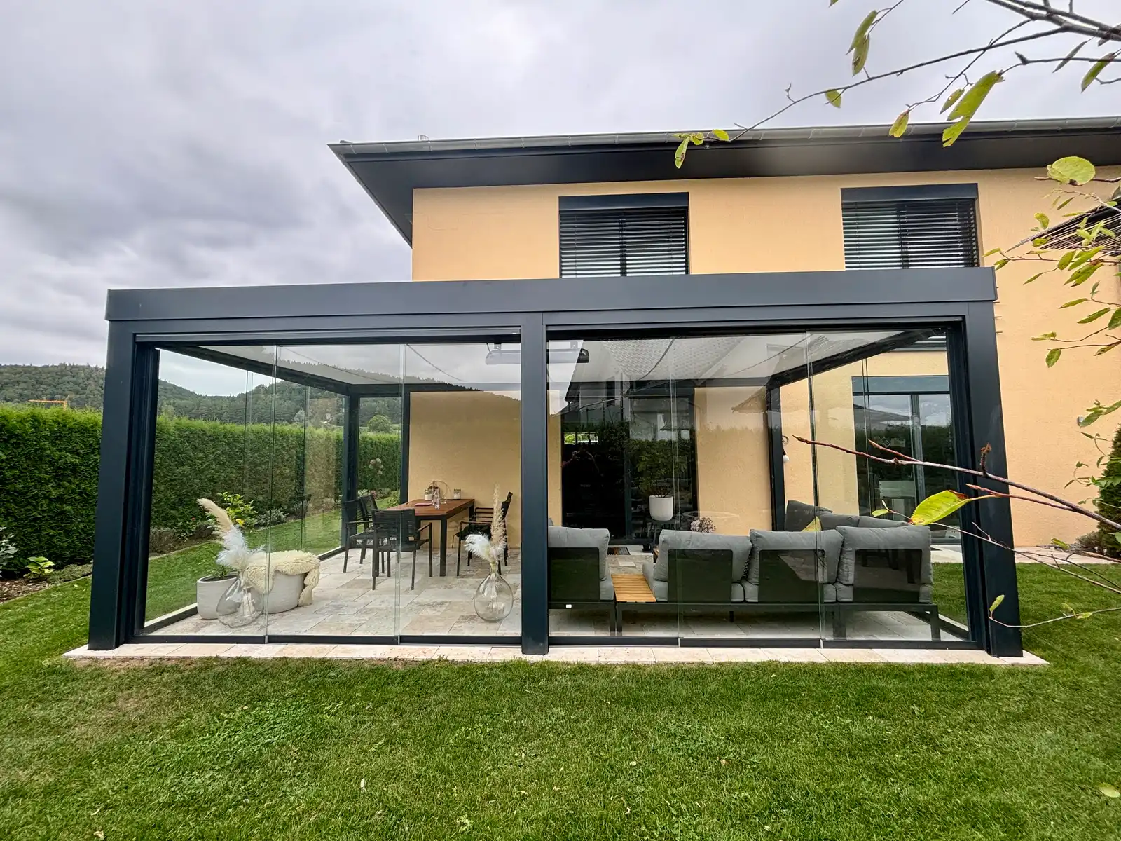 Glashaus mit Ganzglas-Schiebewänden an einem Einfamilienhaus in Wurmlingen bei Tuttlingen, dahinter Lounge und Esstisch, eines der zehn Projektbeispiele aus diesem Kosten-Ratgeber