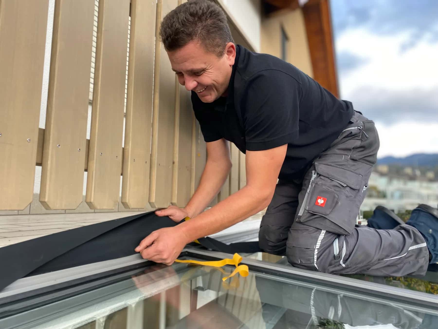 Monteur von Wild & Kienle arbeitet auf dem Glasdach einer Terrassenüberdachung
