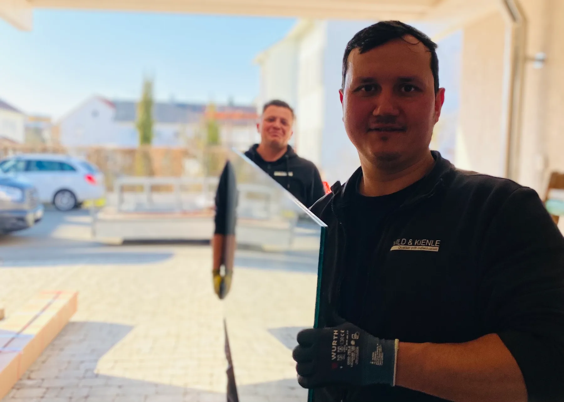 Zwei Monteure von Wild & Kienle tragen ein Glaselement zur Terrassenüberdachung