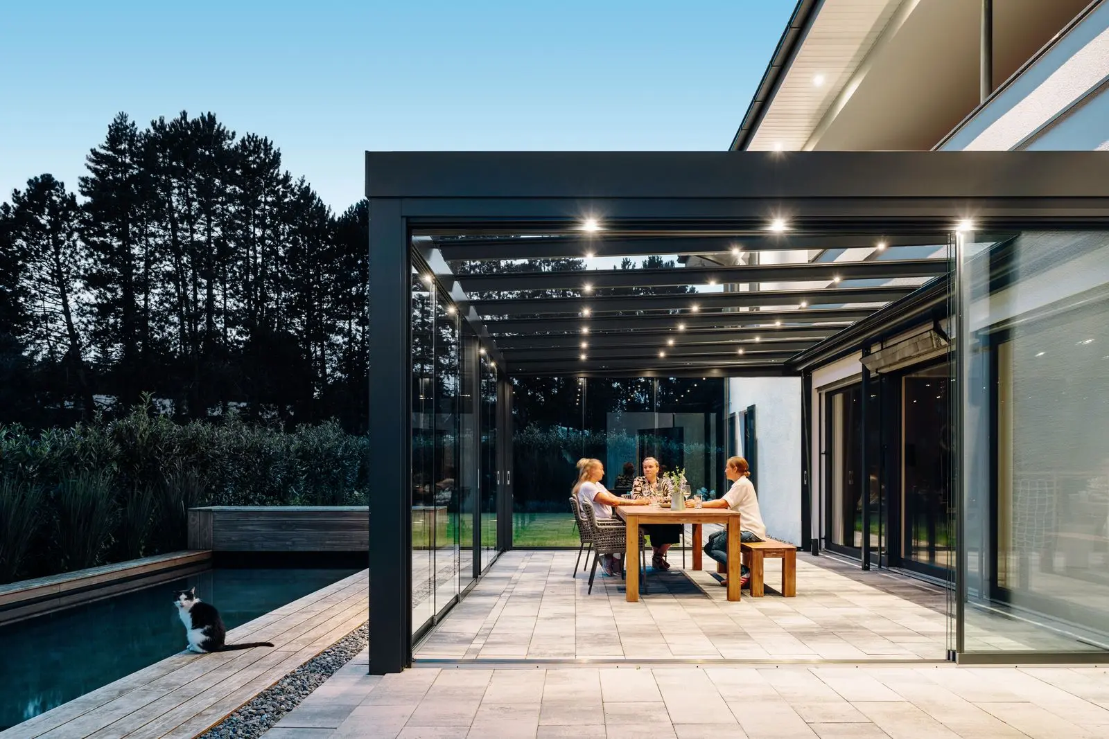 Kubisches Terrassendach SDL Acubis am Abend mit integrierten LED-Spots über dem gedeckten Tisch
