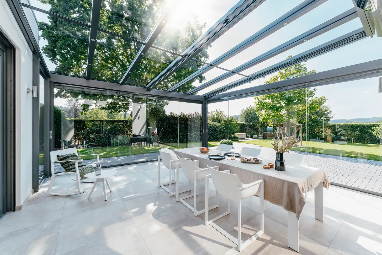 Sonnendurchflutete Innenansicht unter dem geneigten Glasdach des SDL Atrium Plus mit Blick in den Garten