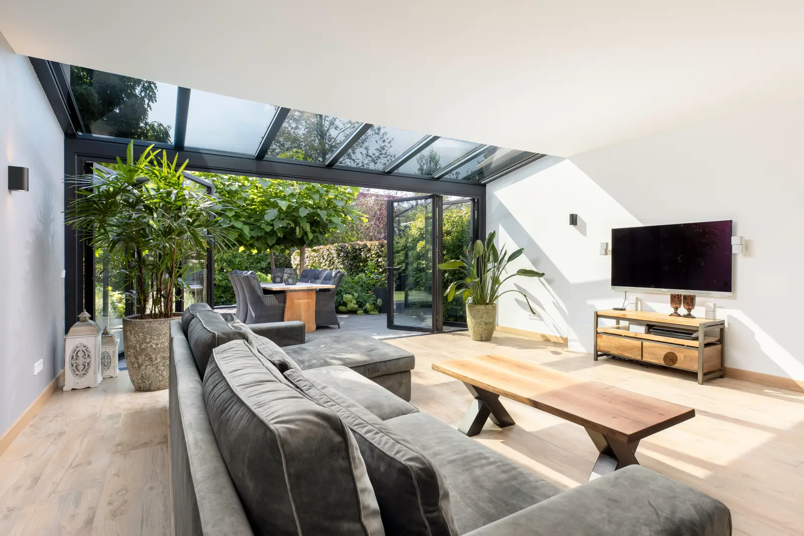 Voll möblierter Wohn-Wintergarten SDL Akzent Plus mit Sofa und Blick durch das Glasdach in den Garten
