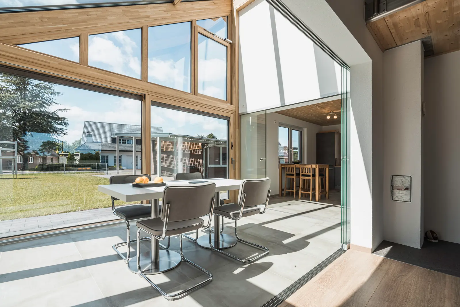 Holz-Alu-Wintergarten SDL Avantgarde innen mit Essplatz und weit geöffneter Verglasung zum Garten