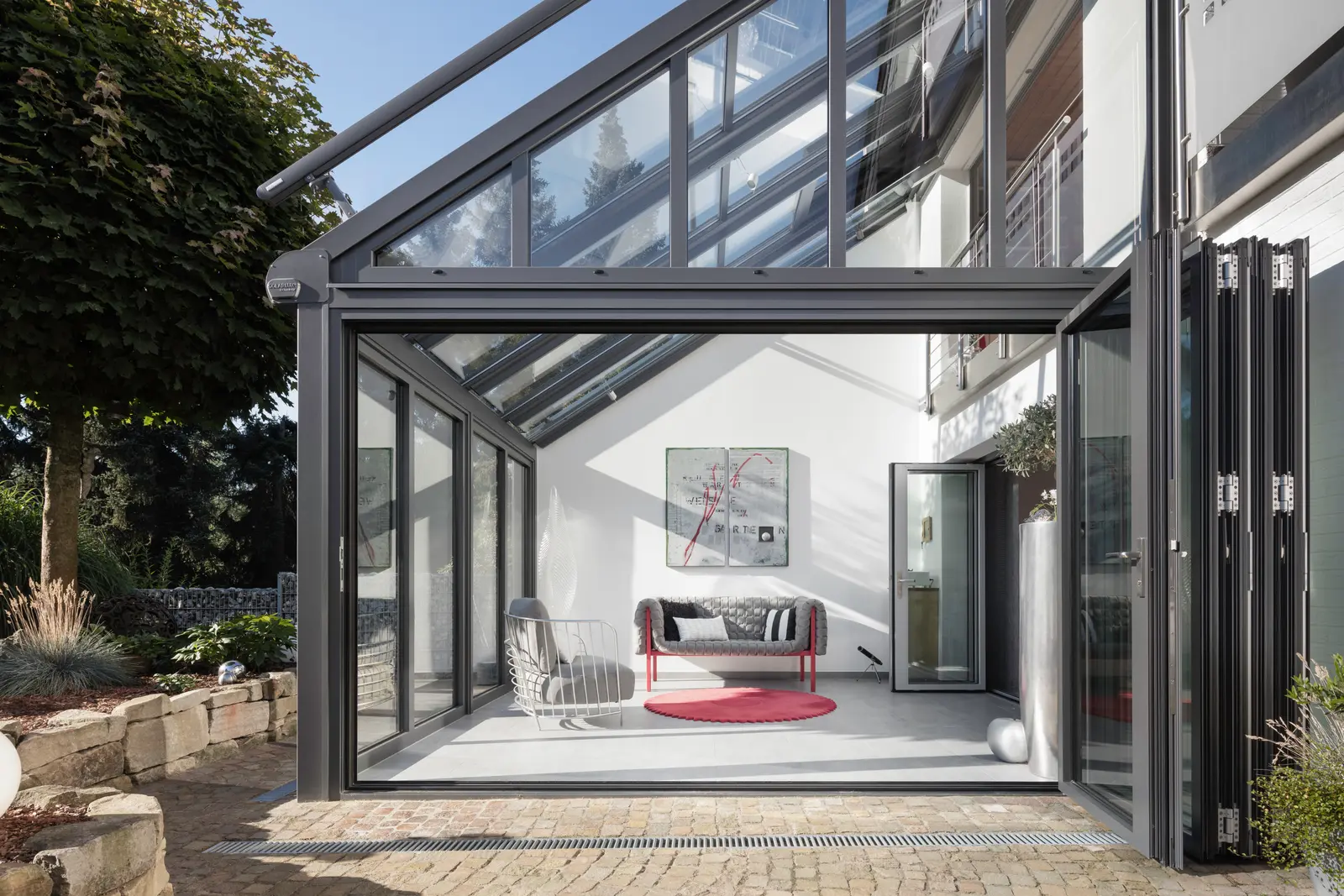 Anthrazitfarbener SDL Nobiles Wintergarten mit komplett geöffneter Glas-Faltwand zur Terrasse