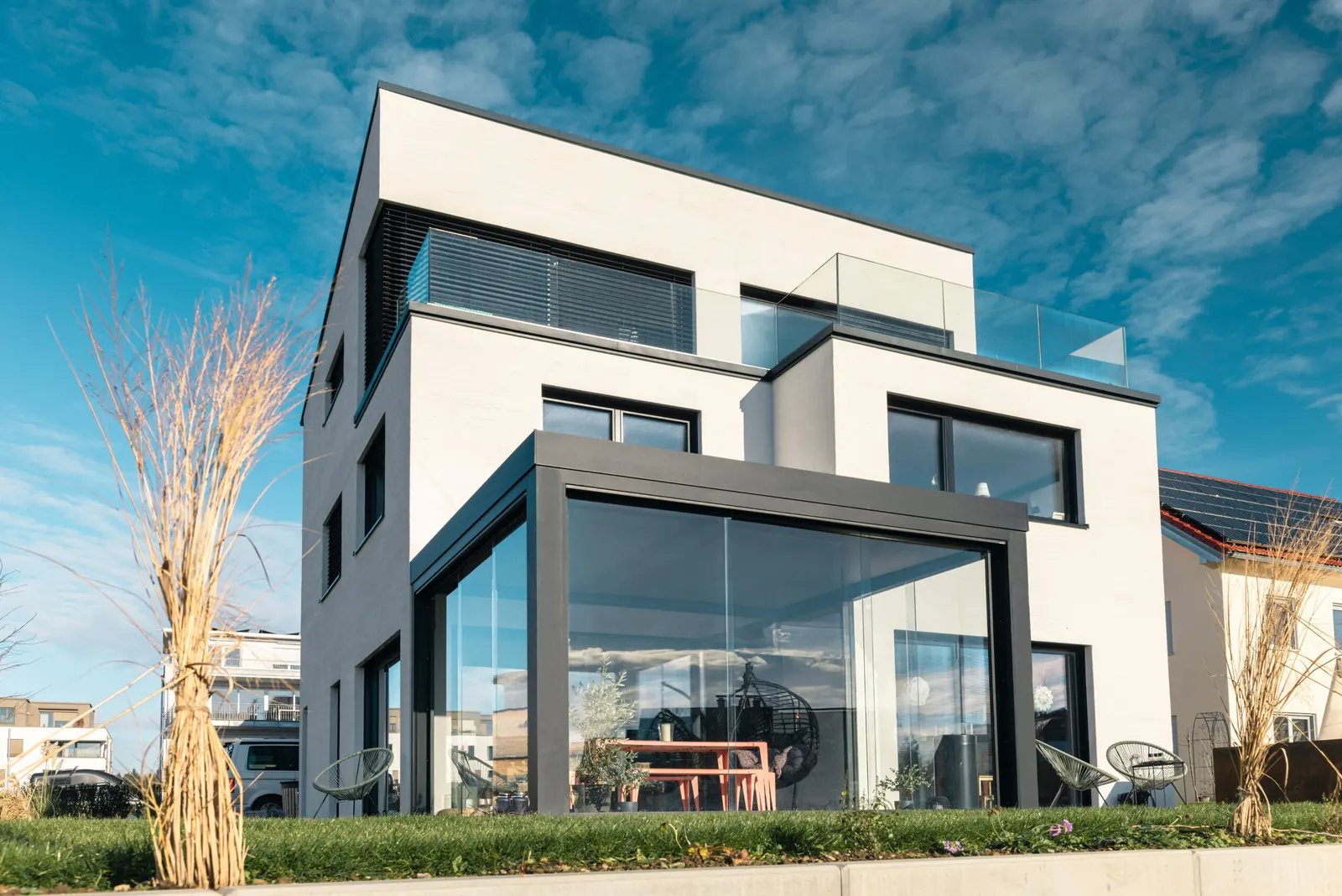 Terrassenüberdachung aus Glas und Aluminium an einem Wohnhaus, davor die Terrasse mit Sitzgruppe