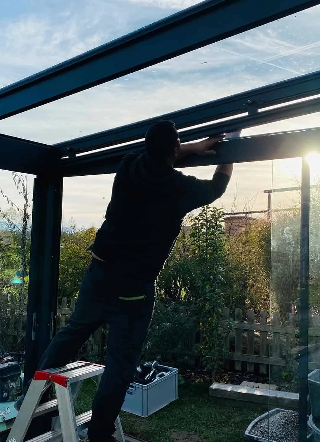 Monteur richtet das Trägerprofil eines Glasdachs in der Abendsonne aus
