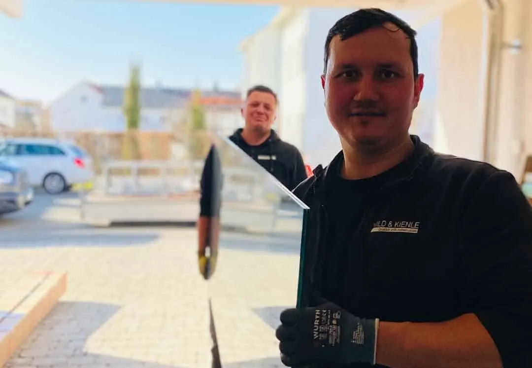 Monteur von Wild & Kienle trägt eine Glasscheibe zur Montage