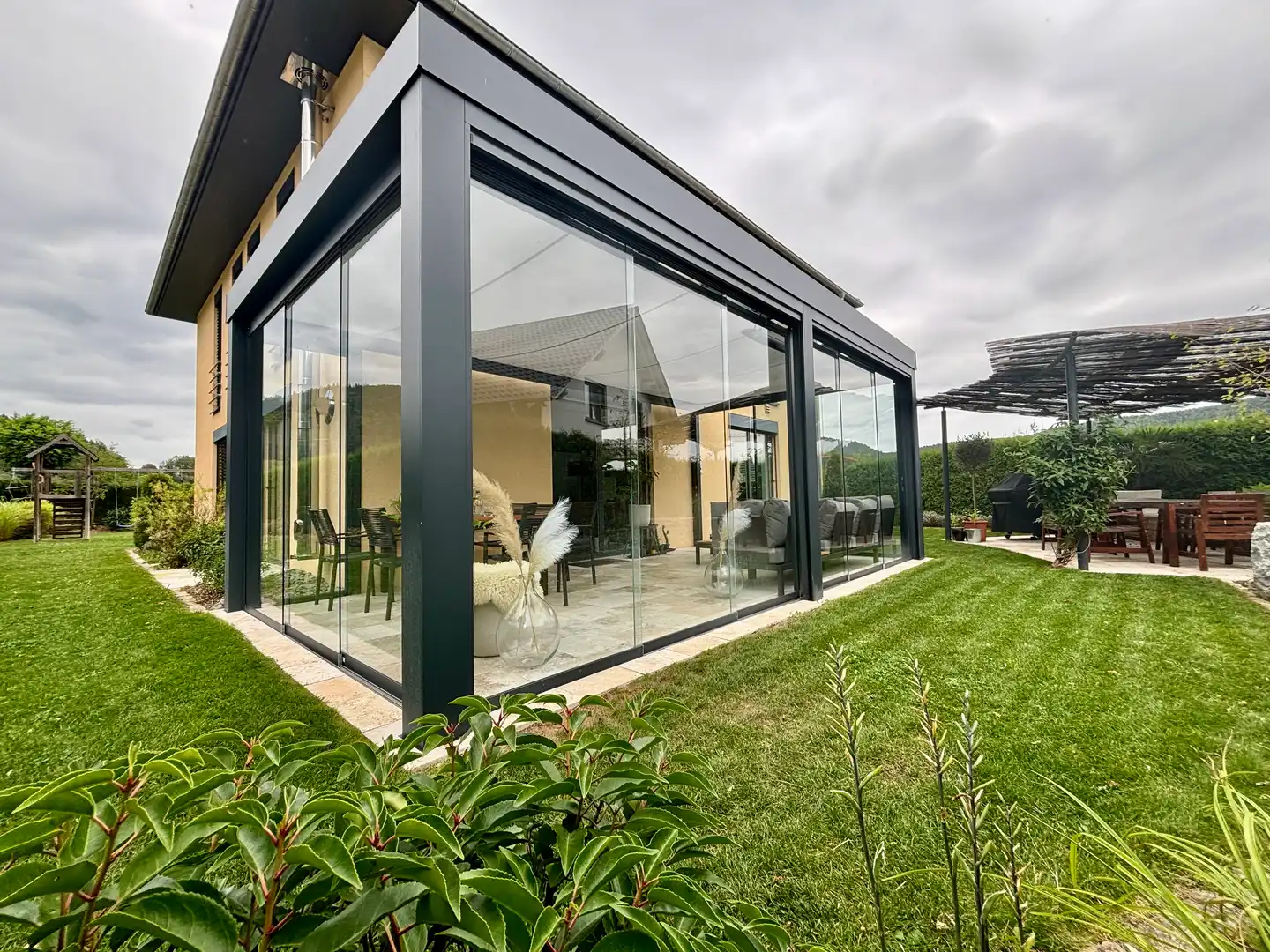 Kubisches Glashaus mit Glas-Schiebewänden an der Hausecke eines modernen Wohnhauses in Wurmlingen
