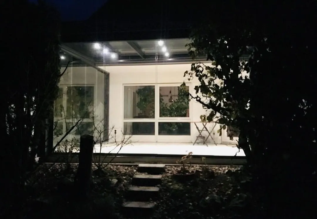 Der beleuchtete Kaltwintergarten bei Nacht, die LED-Spots unter dem Glasdach eingeschaltet