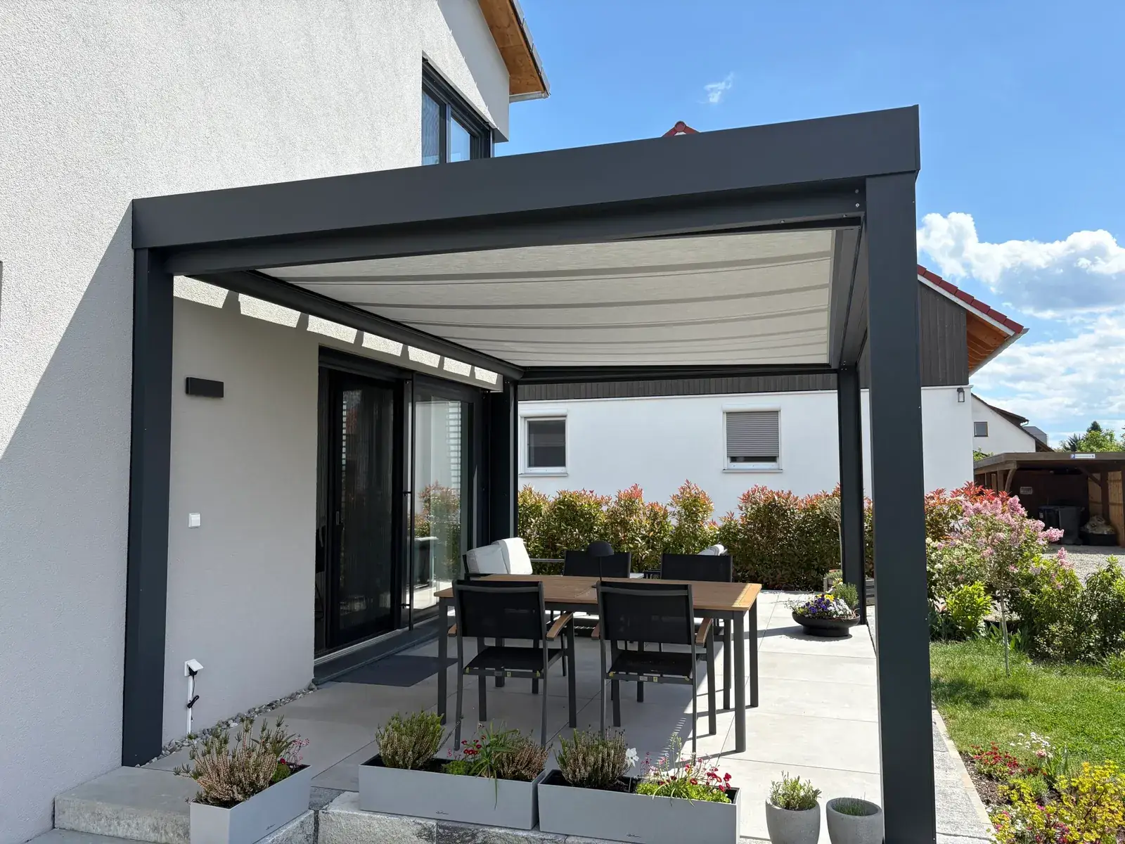 Der Essplatz unter dem Terrassendach, darüber die ausgefahrene helle Unterdach-Markise