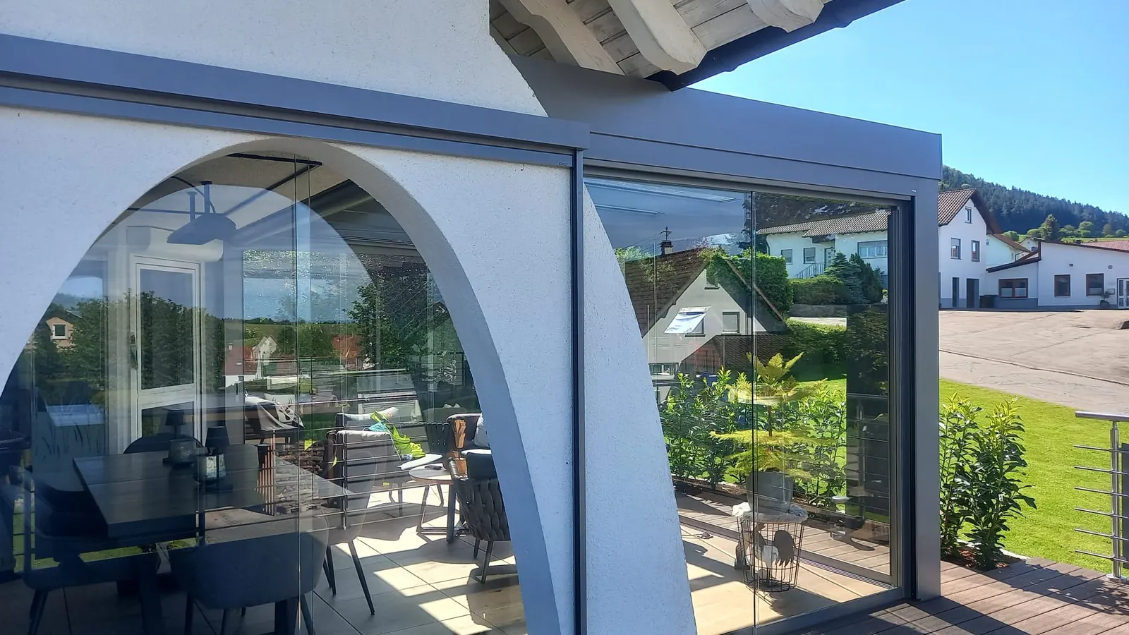 Der weiße Rundbogen an der Stirnseite der Terrasse, rechts daneben die Glaselemente unter der Dachkante