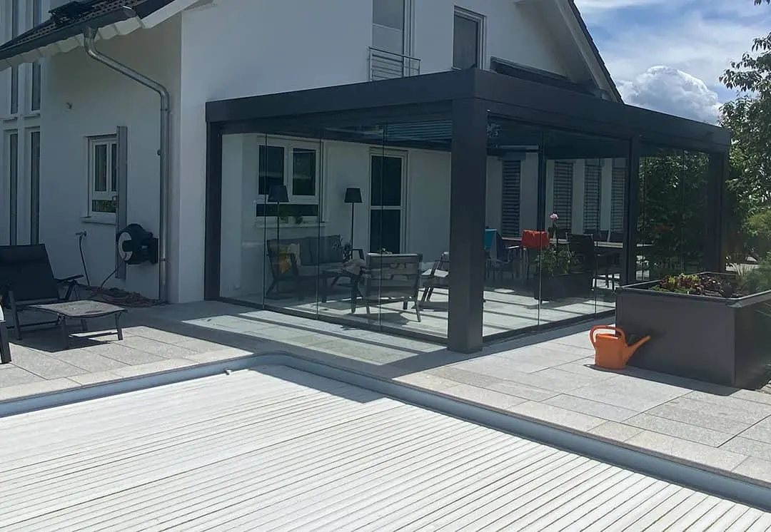 Blick über die geschlossene Poolabdeckung zum verglasten Terrassendach am Haus