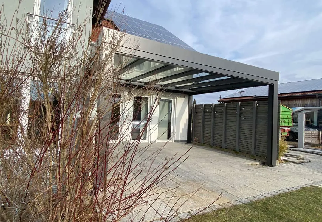 Das kubische Terrassendach von außen, unter der geraden Blende die Glasfläche, rechts die graue Holzlattenwand