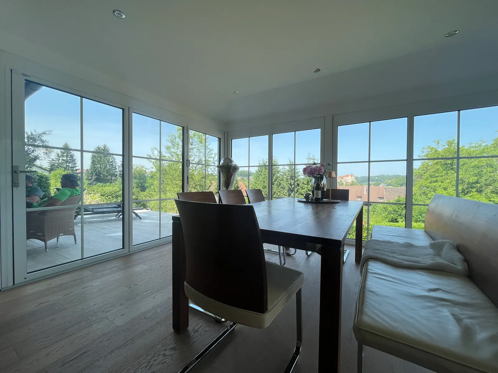 Blick durch den Wintergarten, links die offene Faltwand zur Terrasse, ringsum Sprossenfenster