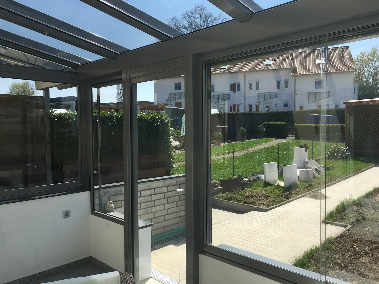 Blick durch die Schiebefenster in die Nachbargärten, vorn die verputzte Brüstung mit der grauen Steinabdeckung