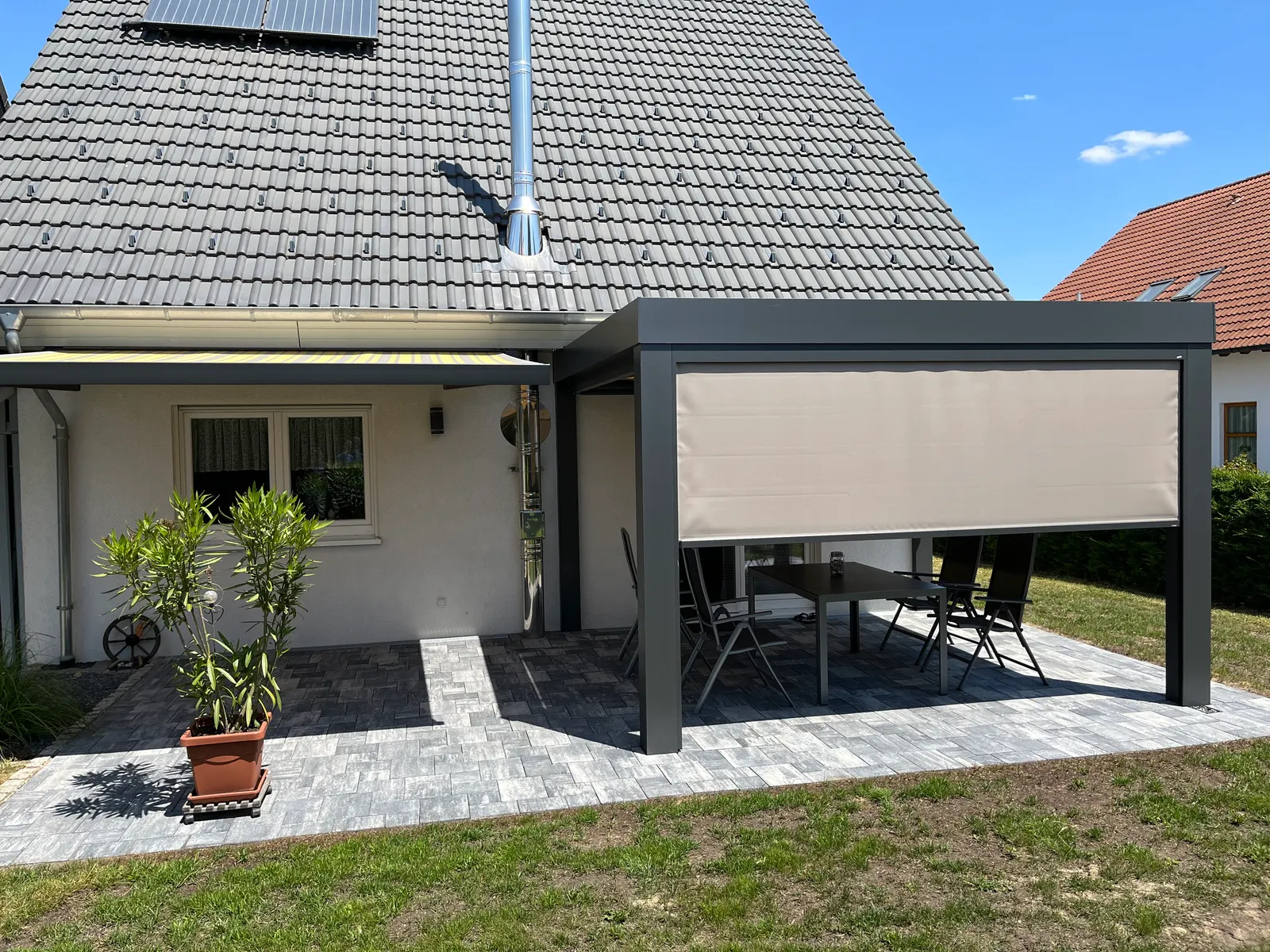 Die Senkrechtmarkise steht auf halber Höhe, darunter bleibt der Blick in den Garten frei